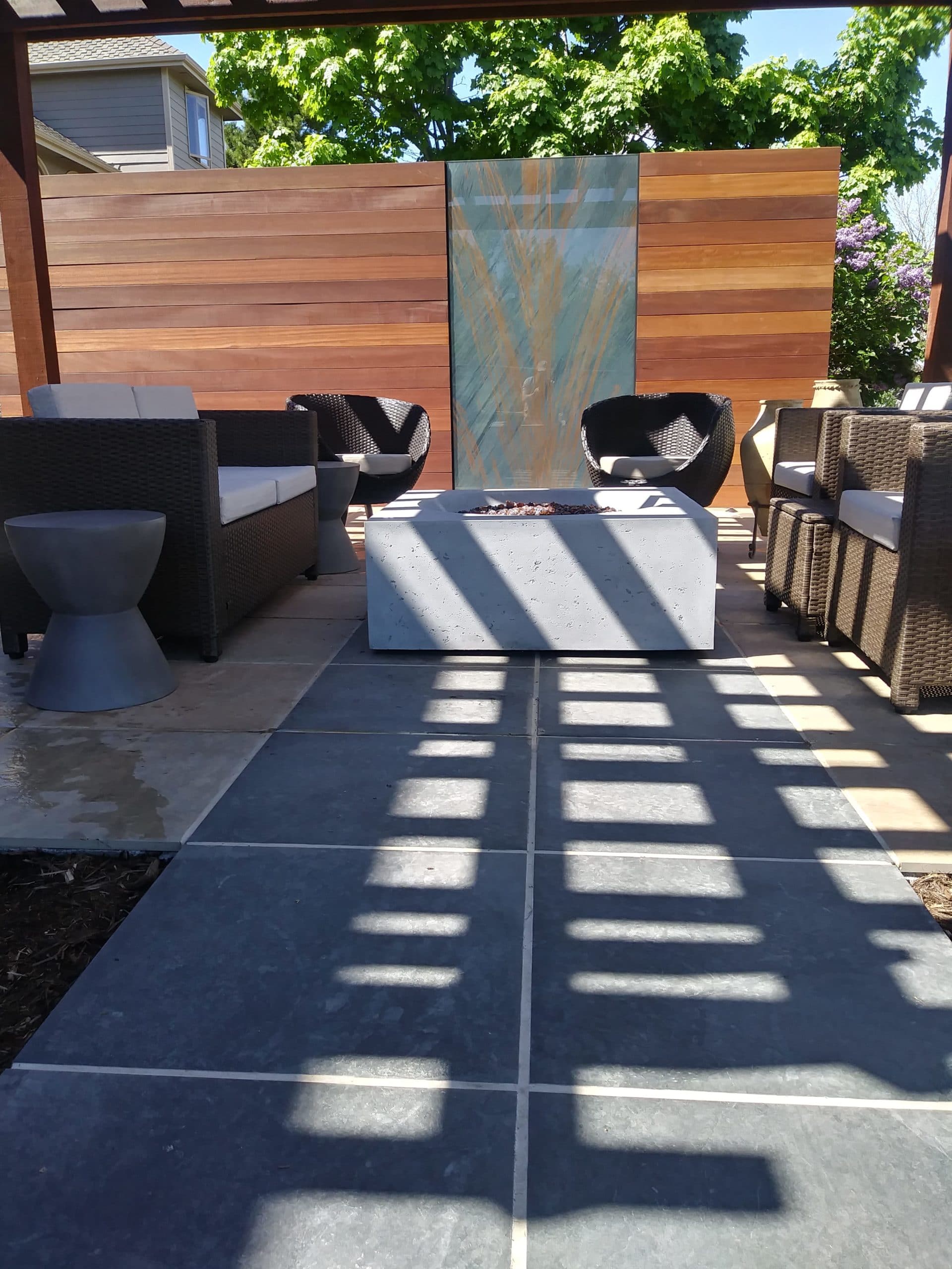 Concrete bowl fire pit with pergola and flat stone patio.