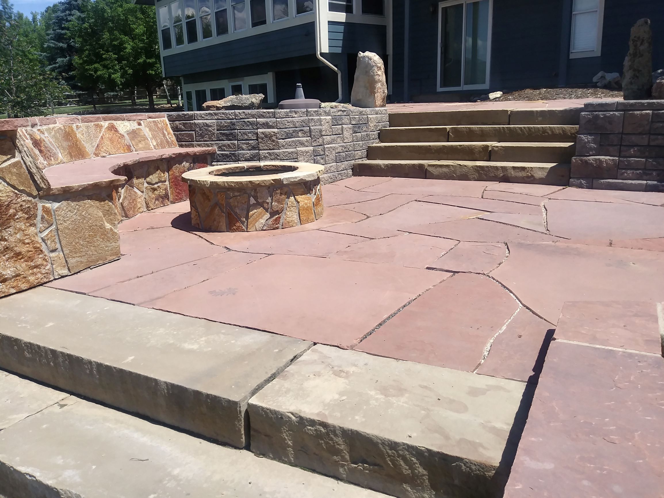 Flat stone patio with fire pit and bench seating. flat stone steps down to patio.
