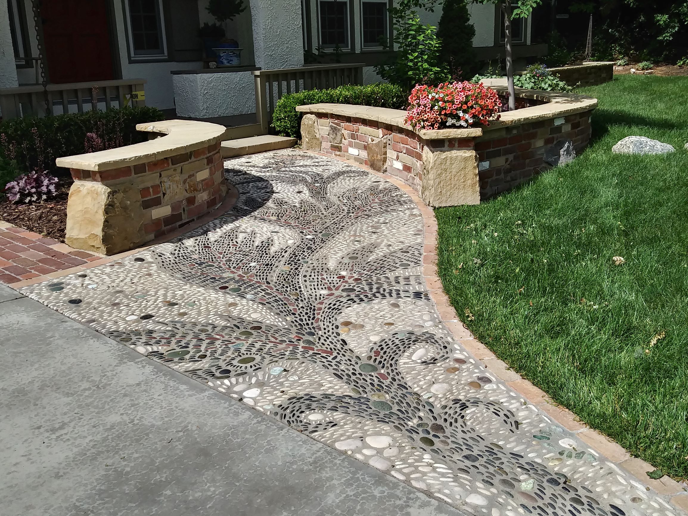 Small mosaic pathway with brick half walls and flat stone tops.