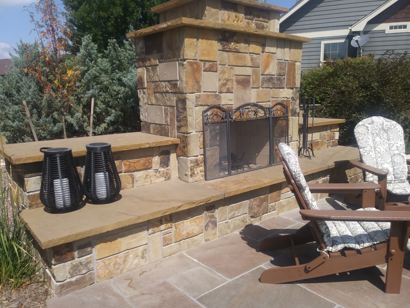 Outdoor Fireplace with large stone chimney and seating area in front.