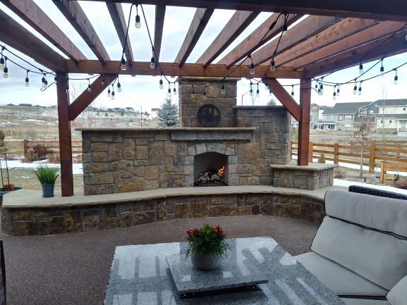 Exterior fireplace with Pergola. Set in river stone with hearty hearth in front,