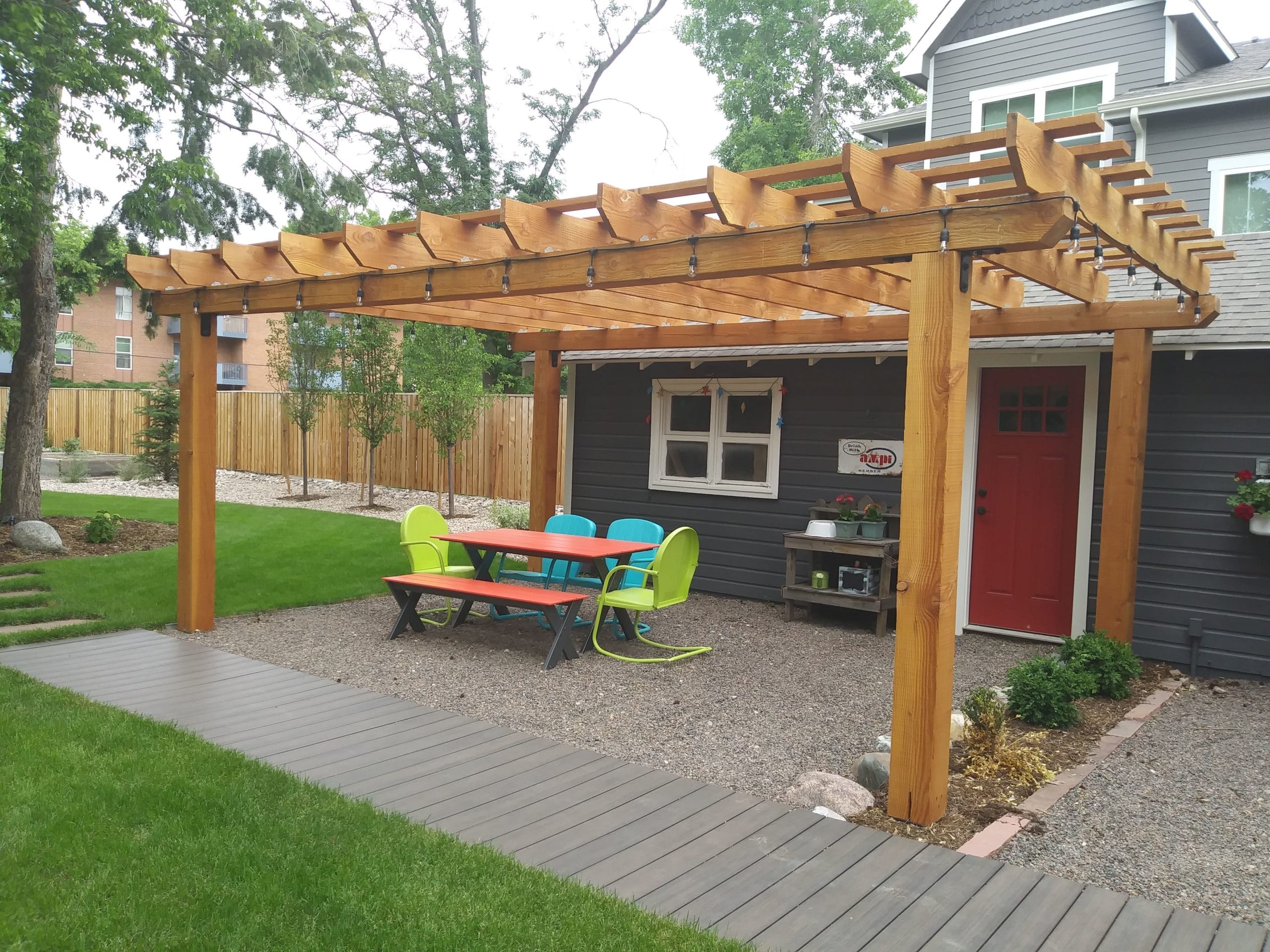 Small gravel patio with seating and pergola over head.