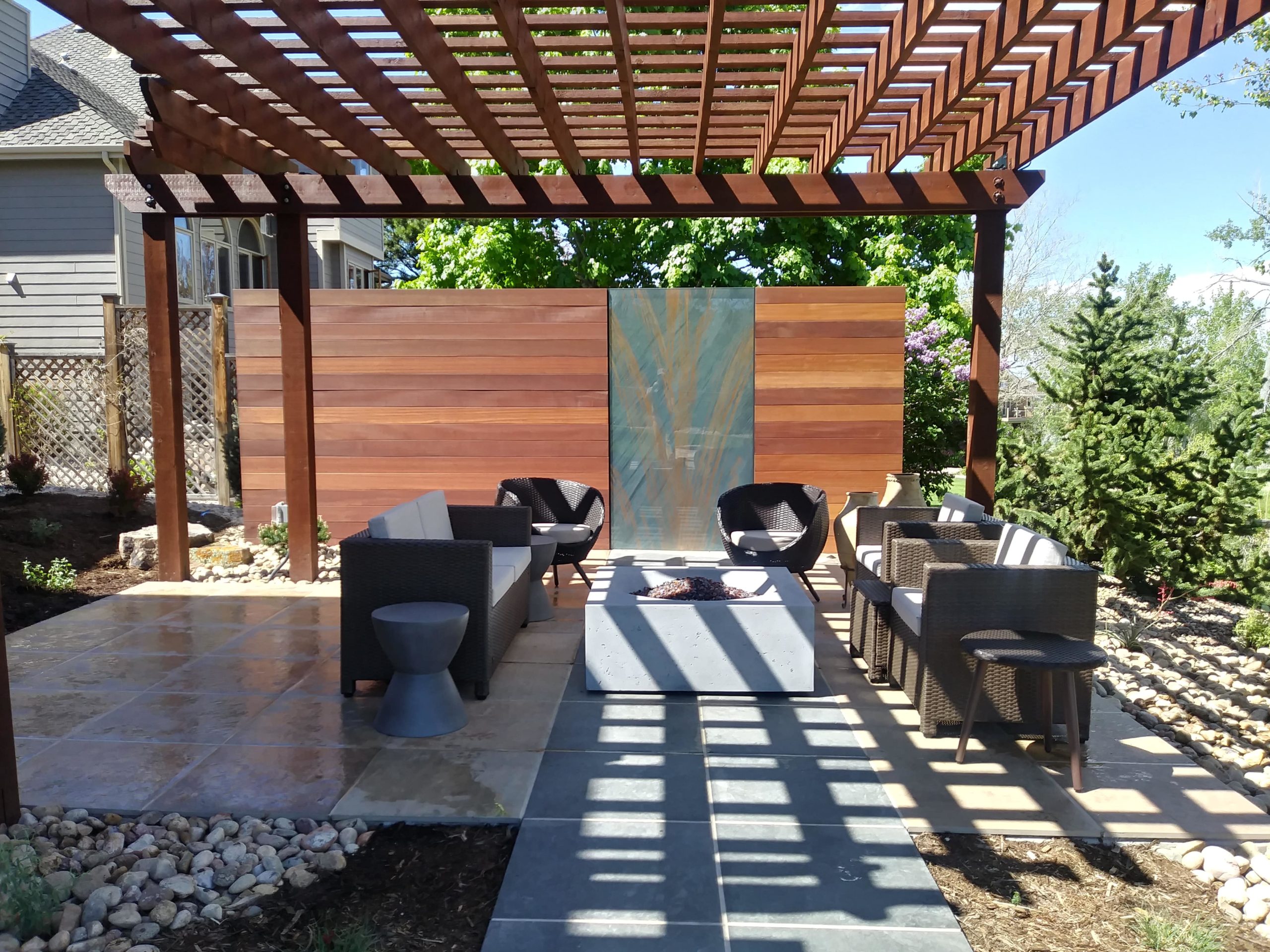 Concrete bowl fire pit with pergola and flat stone patio.