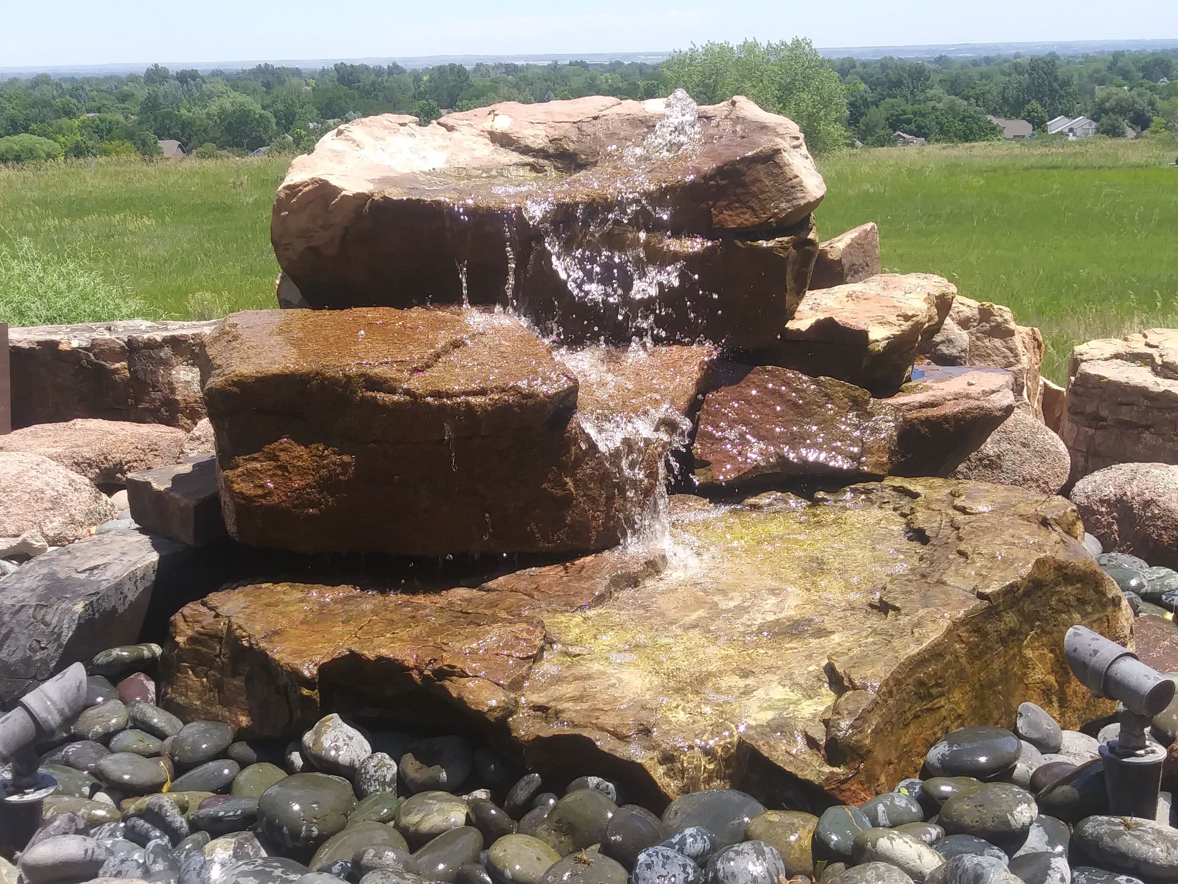 Large rock water feature with landscape lighting.