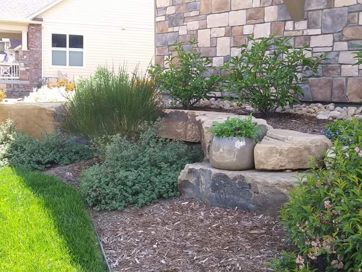 Large decorative rocks with mulch and large rocks. Filled with low maintenance plants and bushes.