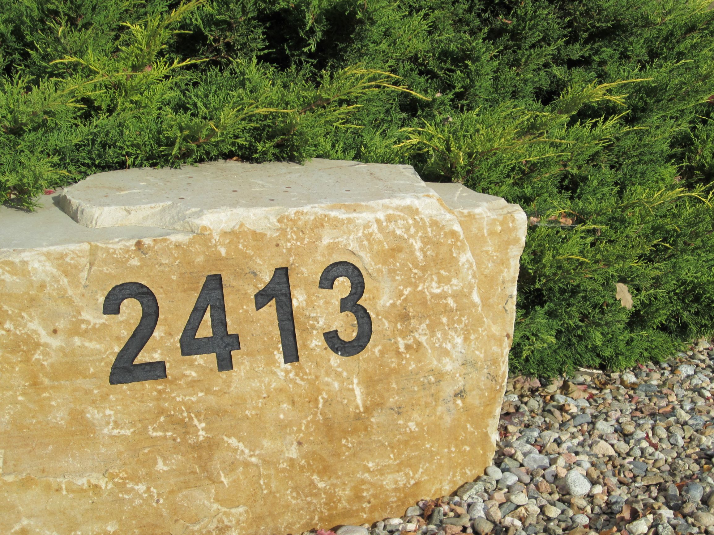 Large decorative rock with address engraved into it.